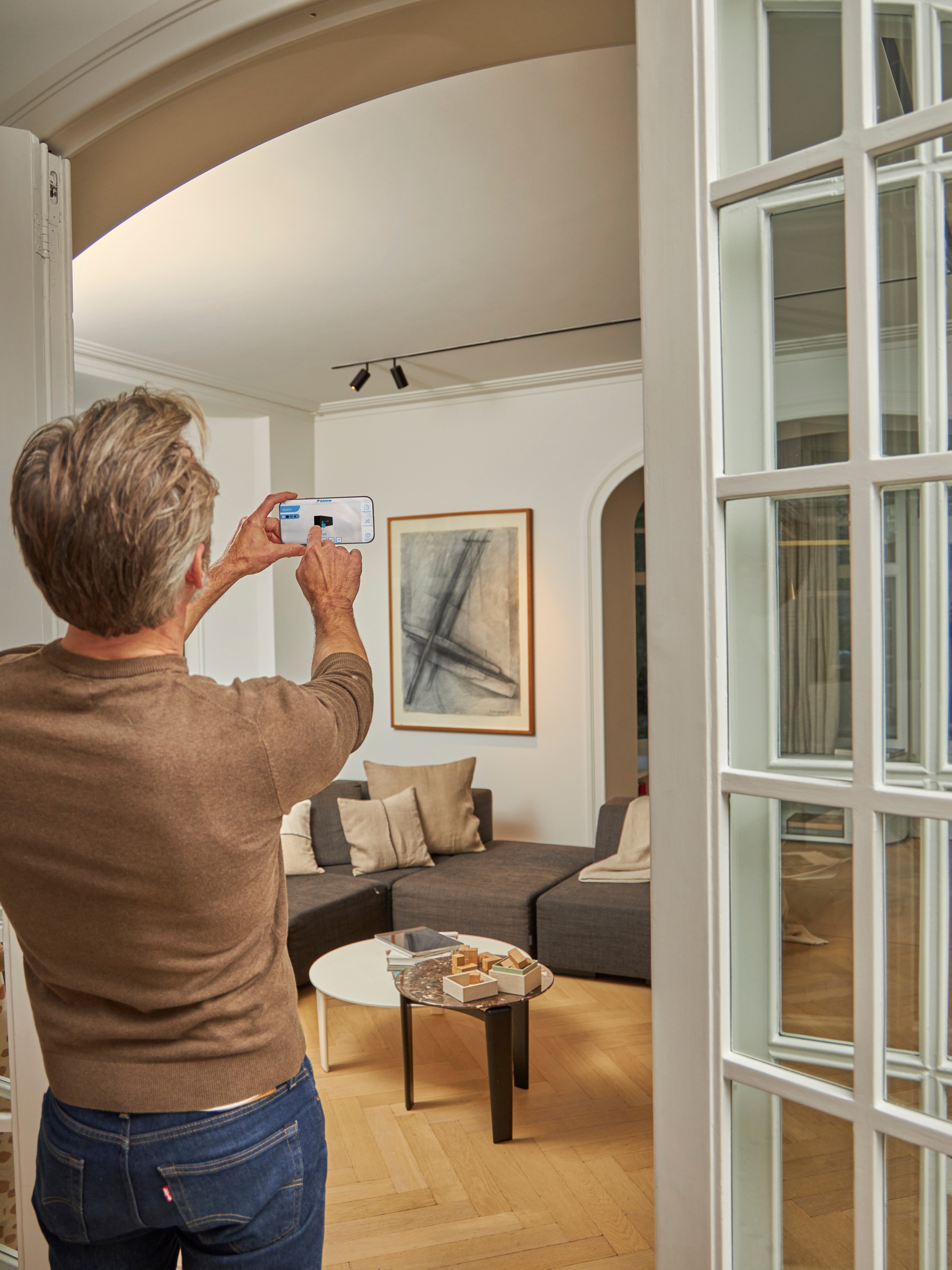 Man using the 3D app to visualize an indoor unit in his living room interior
