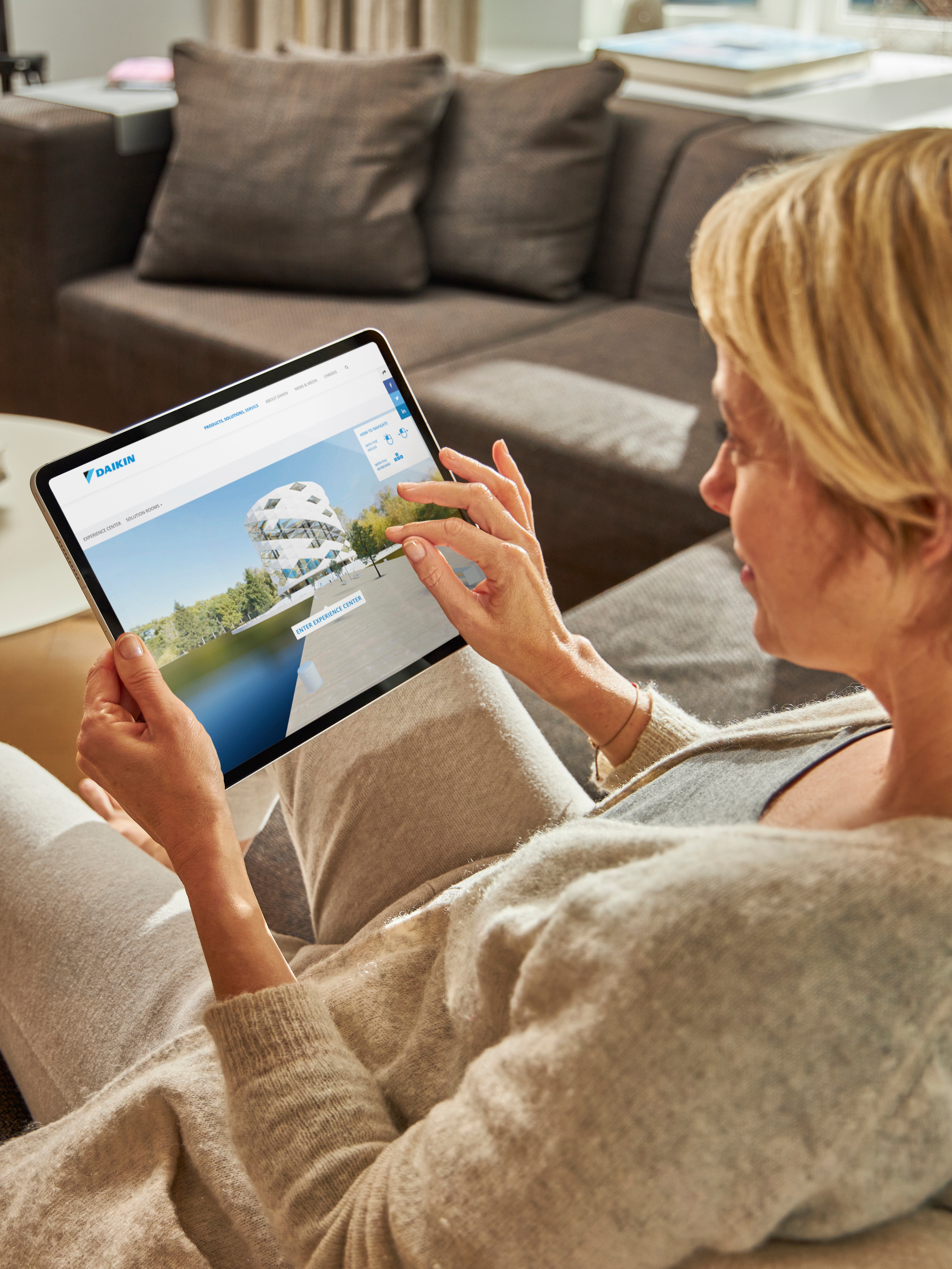 Woman visiting the virtual experience centre on her tablet while relaxing on her couch