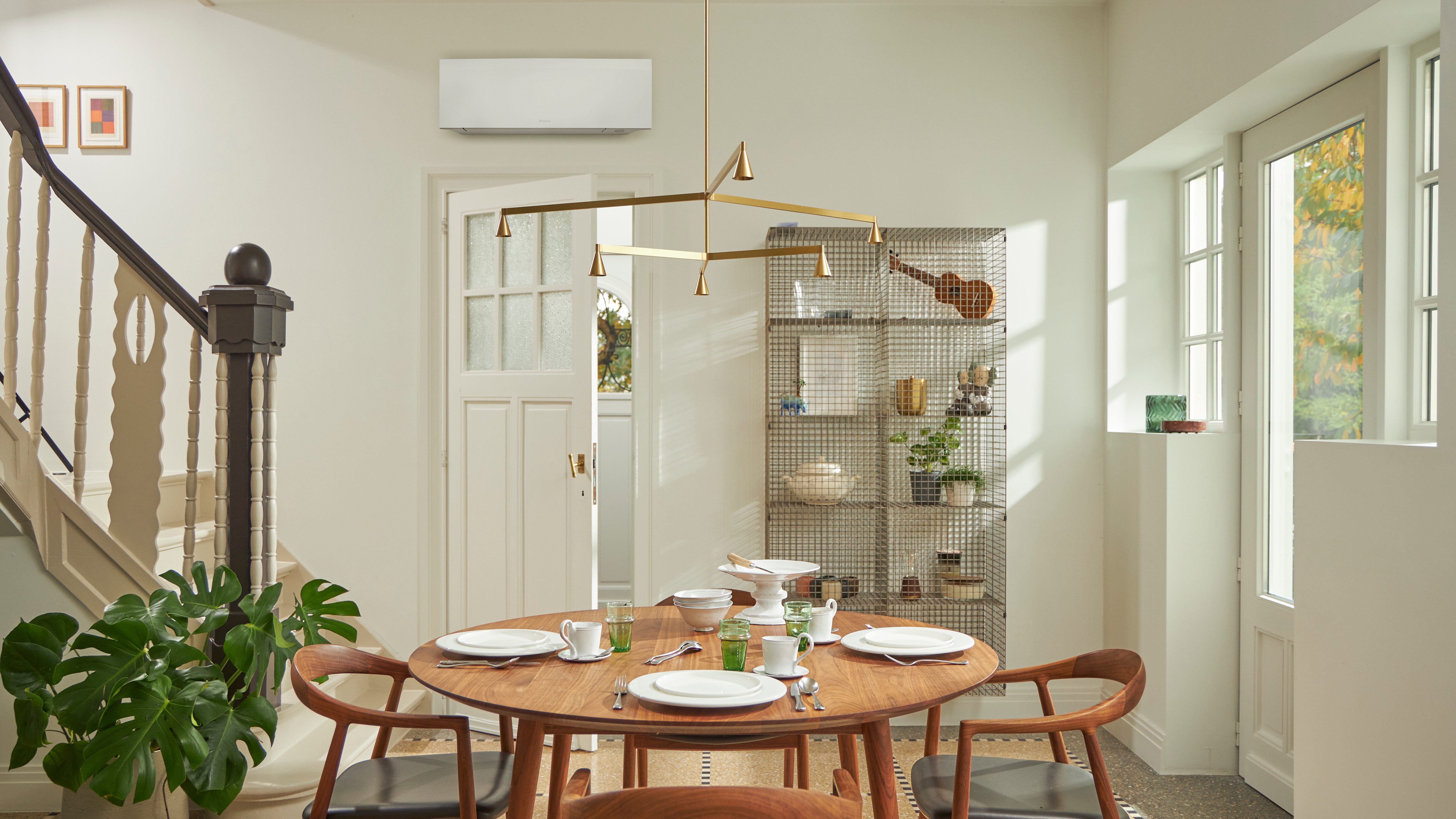 Room with big window, wooden table, and a black wall-mounted climate solution